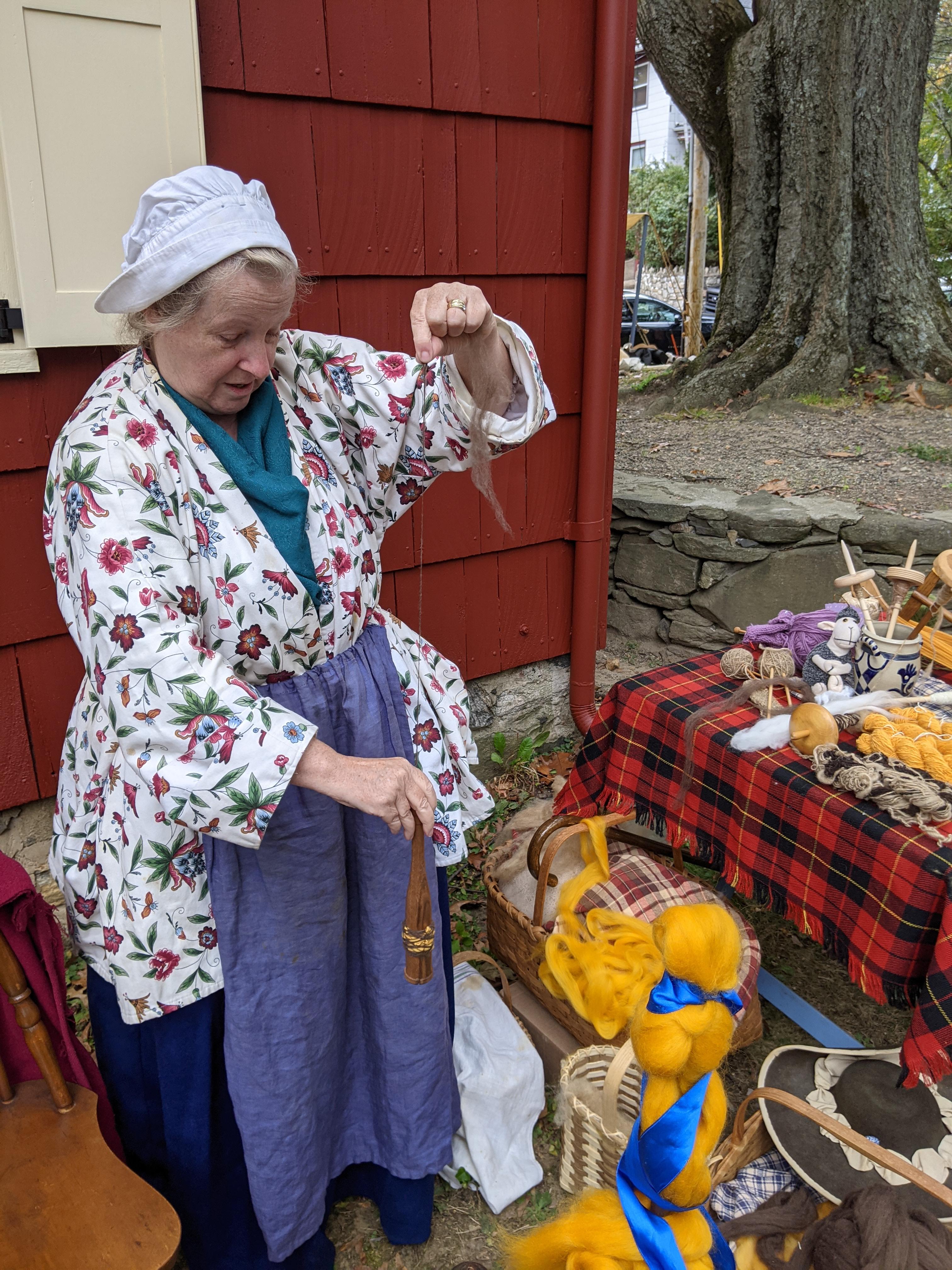 Spinning with a Scottish dealgan drop spindle during the Battle of White Plains event, October 2021